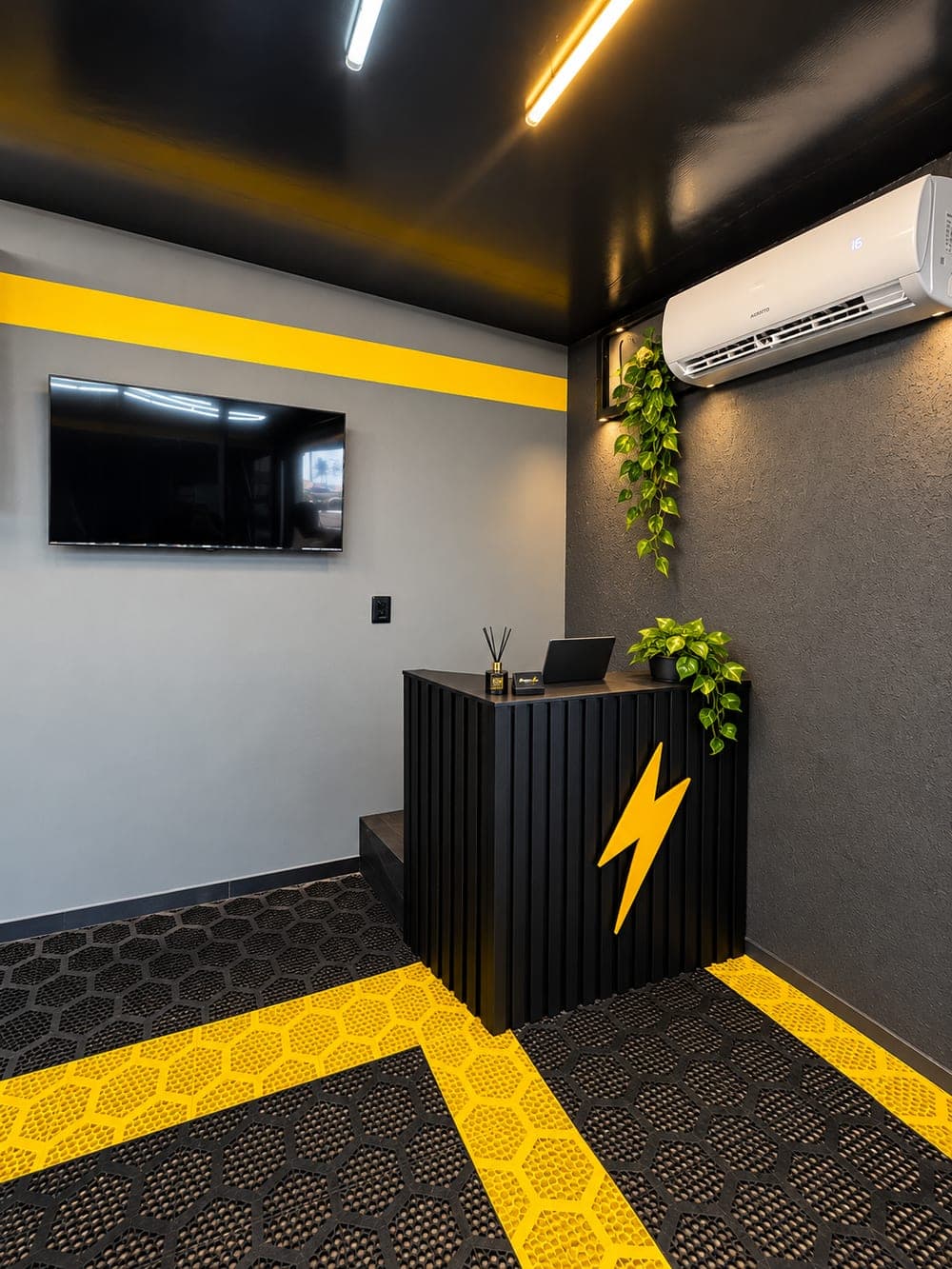 Recepção da PitStop084 com balcão preto e o raio amarelo da marca