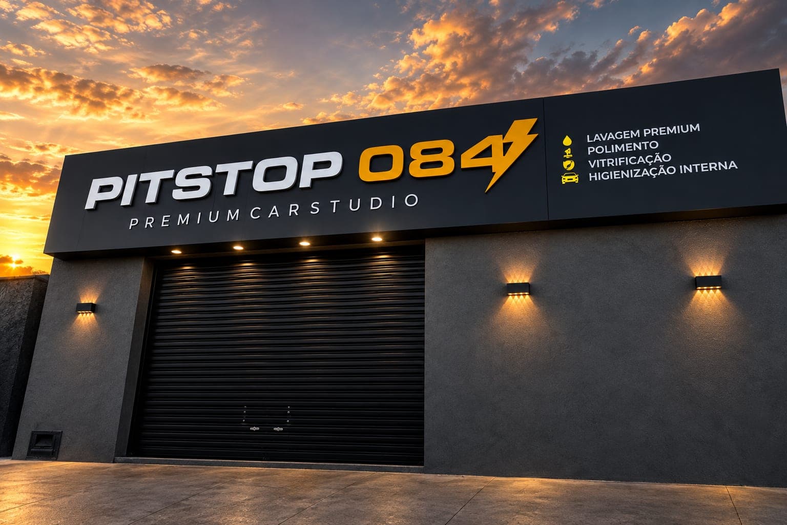 Fachada da PitStop084 Premium Car Studio ao entardecer, com o letreiro preto iluminado e o portão do box