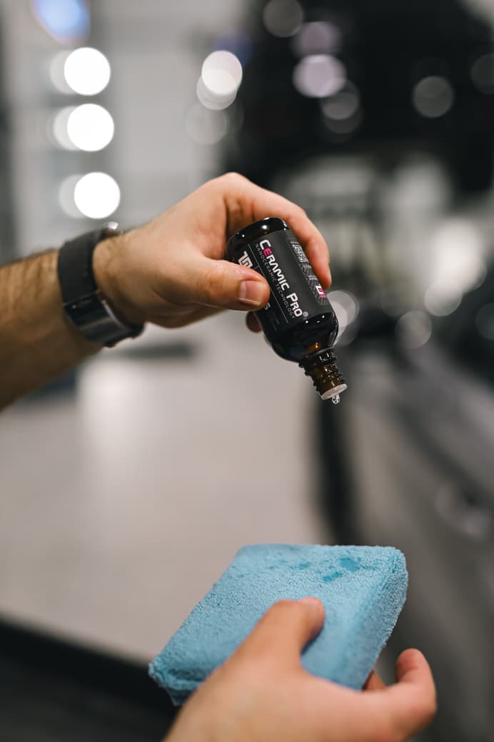 Aplicação de vitrificador em um aplicador de microfibra, com o carro ao fundo